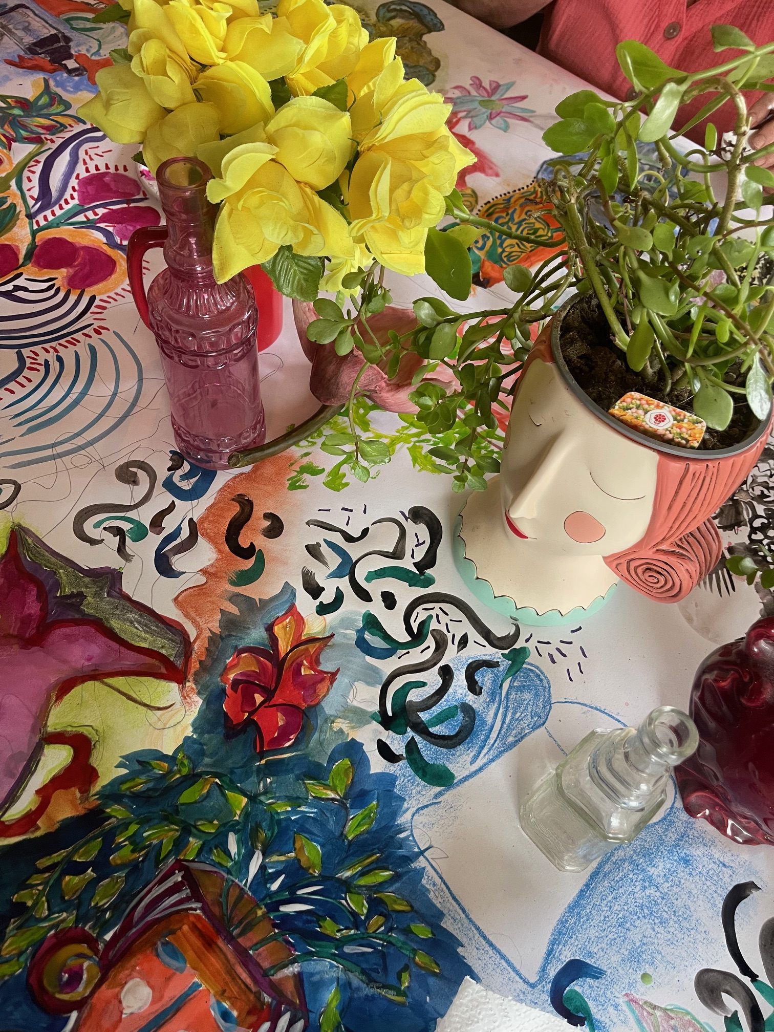 Close-up of colourful workshop drawings, flowers, and layered mark-making on the table