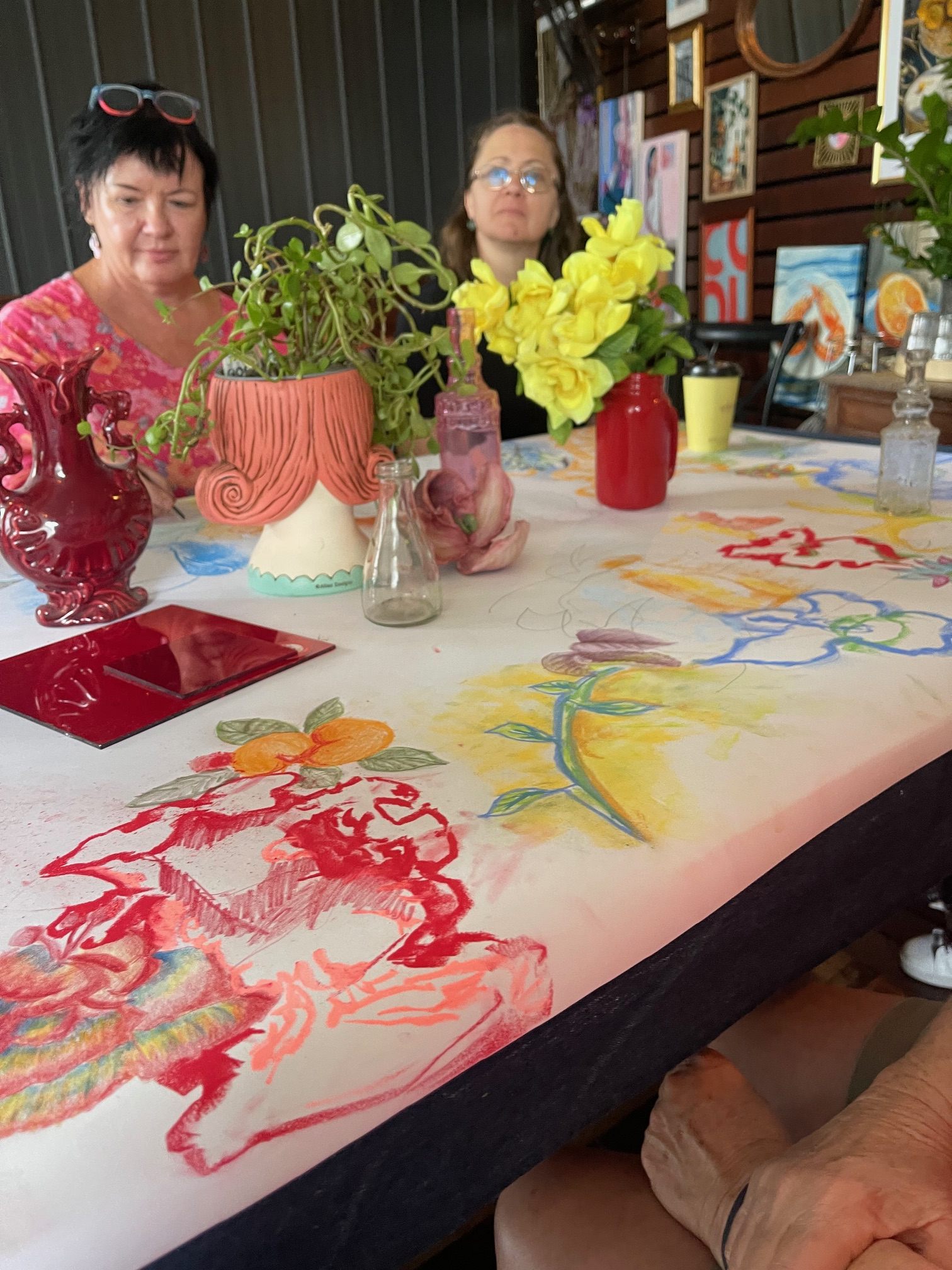 People gathered around the workshop table at Osteria Epoca surrounded by flowers and drawing materials